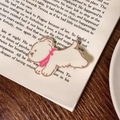 Barrette à cheveux chien blanc mignon avec collier rose sur un livre ouvert - Chiot Blanc / Sans Carte