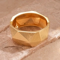 Close-up of golden geometric textured cuff bracelet on a natural stone background - Gold