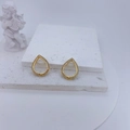 Close-up of golden teardrop earrings with pavé zircons on decorative plaster layers - Gold Water Drop