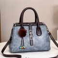 Detail view of stylish tote bag with metal lock buckle and decorative fur ball charm - Blue