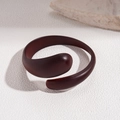 Close-up of minimalist acrylic spiral bangle with matte brown finish on a stone pedestal - 8# Spiral Thick Open (Brown)