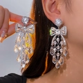 Gros plan de boucles d'oreilles pendantes argentées avec strass brillants sur modèle - Style Nœud Pampille Argent (9# Tige en Argent)