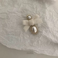 Detail einer cremeweißen Samtschleife-Haarspange mit goldumrandeter Perle - Perle Schleife Stil