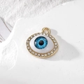 Golden Evil Eye jewelry pendant with blue iris and rhinestones on stone surface - Small Rhinestone Blue Eye