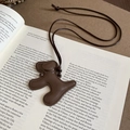 Détail d'un collier pendentif chiot marron avec surpiqûres sur un livre ouvert - Collier-Café(HN10100) / café