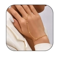 Elegante bracciale anello dorato con catena di perline indossato su una mano di modella - Perle di riso a strato singolo dorate