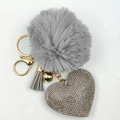 Detail of grey fluffy pompom keychain with rhinestone heart and golden metal bell charms - Gray
