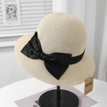Detail of elegant beige straw sun hat with black bow and UV protection tag on stand - Beige Hat With Black Bowknot