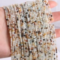 Hand holding assorted 2mm natural gemstone round beads for DIY jewelry making - Amazonite