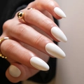 Glossy white almond shape press-on nails shown on hands with gold ring accent - White