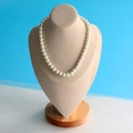 Classic round creamy white pearl necklace displayed on a beige velvet jewelry bust stand - Large Beige Velvet