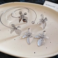 Detail view of silver floral metal cuff bracelet and matching earrings on ceramic tray - Silver (4-Piece Set)