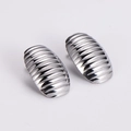 Gros plan de boucles d'oreilles ovales argentées avec texture rayée sur fond blanc pur - Couleur Acier