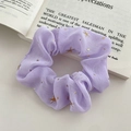 Purple chiffon scrunchie with golden stars pattern on an open book background - FQ1068E Purple Star Scrunchie