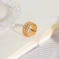 Close-up of gold hollow woven chain ring on an open book in a warm indoor setting - Double Layer Chain Link Ring