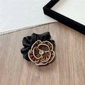 Detail of elegant satin camellia hair scrunchie with brown petals and white piping - Coffee