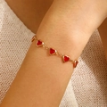 Detailopname van een vergulde armband met rode hartjes aan de pols van een vrouw - Eenvoudig Rood Hart Enkel (4940) / Rood