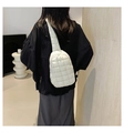 Beige quilted puffer chest bag with crossbody strap shown on a model for size - White