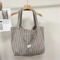 Detalle del bolso tote de lona a rayas grises con bolsillo frontal y etiqueta de marca - Gris a Rayas