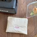 Close-up of cream macaron makeup bag with pink zipper on a wooden table setup - Off-white