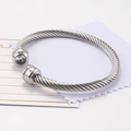 Bracciale rigido a cavo intrecciato argento con un singolo zircone su sfondo pulito - Aprile/Trasparente