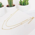 Detail of a double-layered gold snake chain necklace with beads on a minimalist display - Round Snake Chain Gold