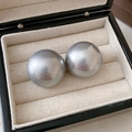Macro detail of glossy silver spherical drop earrings displayed on a soft beige jewelry tray - Round Pearl Studs / Gray