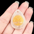 Handheld view of natural amethyst teardrop pendant with golden tree of life engraving - White Crystal