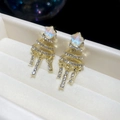 Macro shot of gold star drop earrings with spiral tassels and shimmering rhinestones - Gold