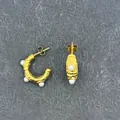 Detailed view of C-shaped gold textured earrings with small pearls on stone background - C-Shape Pearl