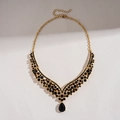 Detail of V-shaped gold necklace with black round and teardrop rhinestones on white - Necklace-Black