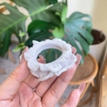 Detail of a white ruffled fabric scrunchie being held, showing soft texture and premium style - Grey/White