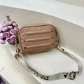 Beige cameratas met litchi-textuur en brede jacquardriem op een stenen achtergrond - Khaki