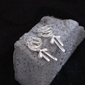 Elegantes ear cuffs de lazo plateados con borlas largas de metal sobre piedra gris natural - Plateado