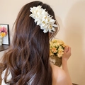 Detailansicht einer eleganten weißen Stoffblumen-Haarspange in gewelltem braunem Haar - Acryl Spinnenlilie Stil (62#) / Weiß
