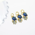 Vue macro de trois pendentifs en zircon bleu ovale avec monture dorée et reflets - Bleu