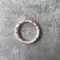 Detail view of floral spiral hair coil with red and green patterns on cement background - White Floral