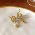 Close-up of golden snake earrings with pavé crystals and red gems on a ceramic tray - 19# Silver Pin Earrings - Gold - Red Gemstone Snake