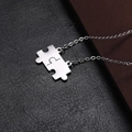 Macro-opname van zilveren puzzelstukjes hangers op zwarte leren achtergrond - O ketting / Zilver