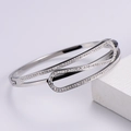 Vista macro de una pulsera plateada con diseño geométrico calado y circonitas blancas - Plateado