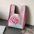 Detail of pink knitted tote bag featuring a large woven rose and textured yarn finish - Rose Red