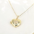 Close-up of golden heart locket pendant with micro-pave cubic zirconia on a white plate - Heart
