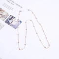 Minimalist golden beaded eyeglass chain with transparent silicone loops on white base - Gold Bead Chain