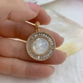 Detailed close-up of a gold Virgin Mary pendant with white shell and sparkling crystals - 26mm / White