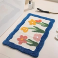 Green floral 3D flocked bathroom rug with orange flowers and a blue wavy border - Tulip