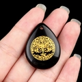 Waterdrop obsidian pendant with golden tree of life inlay, held by hand detail view - Obsidian