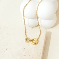 Close-up of golden infinity pendant with cubic zirconia stones on stone base - Gold Half Zirconia Infinity
