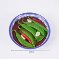 Modelo de comida realista de judías verdes y pimientos rojos en un bol de porcelana azul - Guisante