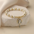 Detail of beaded bracelet featuring gold metal balls, white pearls, and a cute cat pendant - Grey Cat