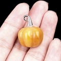 Ciondolo zucca in resina gialla lucida con gancio in argento tenuto in mano - Topazio
